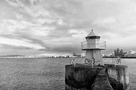 雷克雅未克灯塔塔在石码头在冰岛。灯塔在海上。在海景和天际线的建筑。航海援助和目的地地点。流浪和前往雷克雅未克, 冰岛