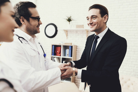快乐的商人与治愈疾病的医生握手。确认