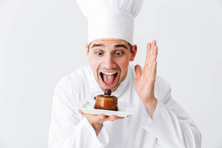 开朗的男人厨师穿着制服，在白色背景的盘子上展示糕点