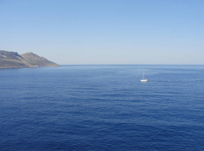 大海，孤独的白帆船和岛屿的海岸线在背景