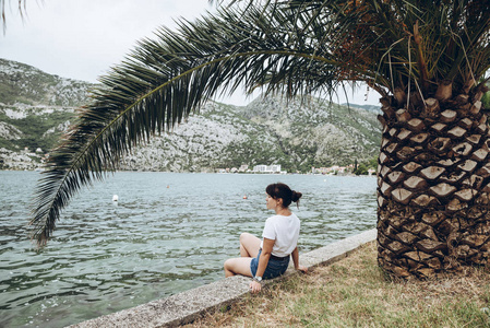 坐在海边看波浪的女人。背景上的山脉。夏季