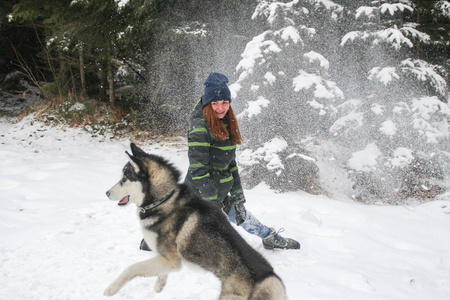 哈士奇狗和一个女孩在树林里跑。 在雪地里玩。 冬天和宠物一起玩。