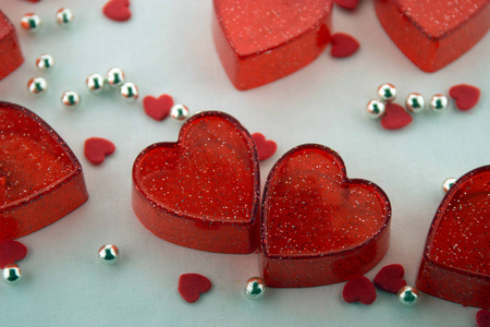 情人节的概念。 小小的红色塑料心脏，小小的红色心脏和白色背景上的银珠。 上面的风景。