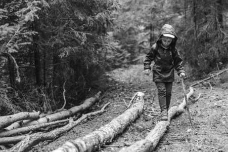 一个女孩拿着棍子走在森林里，黑白相间