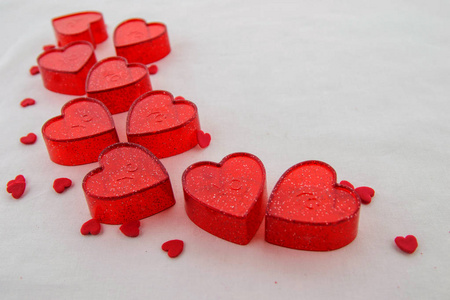 情人节的概念。 小的红色塑料心脏与明亮的点和微小的红色心脏在白色的背景。