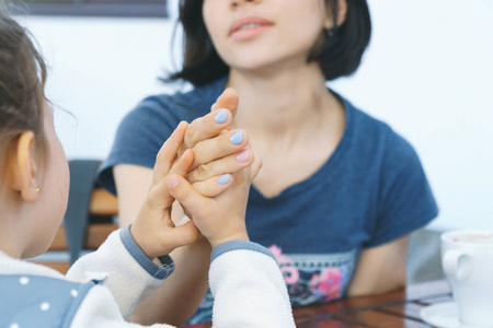 女孩牵着女人的手在桌子上