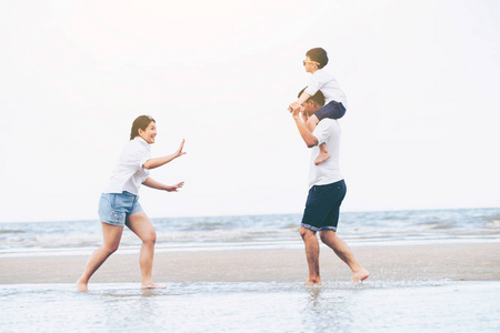 父亲母亲和儿子的幸福家庭在夏天去热带沙滩度假。