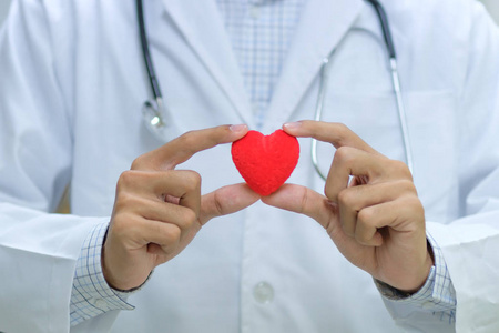 男医生用听诊器手握红色心形在医院。 医疗及健康保险概念