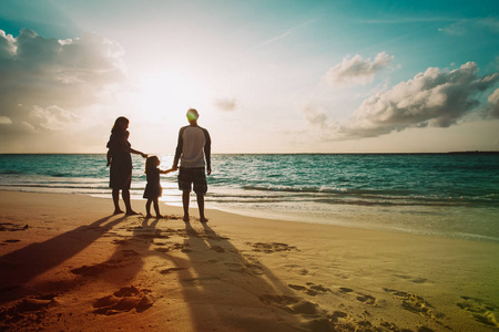愉快的家庭与孩子在日落海滩漫步