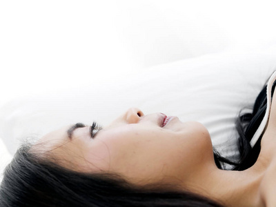 快乐的亚洲女人躺在床上，用复制空间封闭起来。