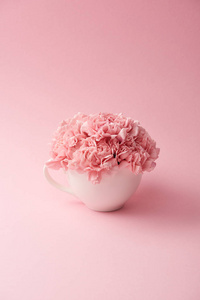 粉红色背景的白色杯子美丽的粉红色康乃馨花