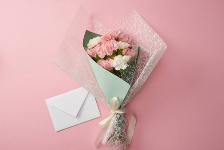 顶部的美丽的嫩花束和白色信封隔离在粉红色。