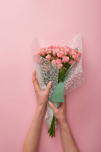 一个女人拿着一束美丽的玫瑰花，被隔离在粉红色上