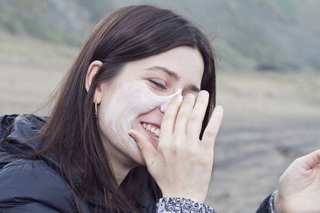 一个年轻的女人在她的脸上抹太阳霜