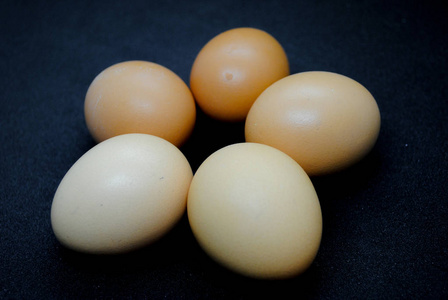 黑色背景下的五个棕色鸡蛋。照片适用于有关食物和健康的故事。