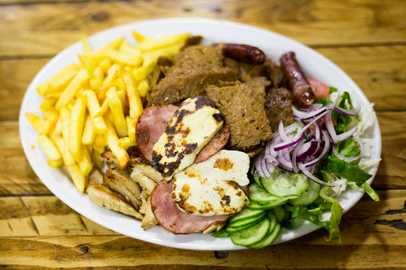 在帕福斯的当地餐馆里，把烤串和哈鲁米和薯条混合在一起。 塞浦路斯岛上的传统塞浦路斯食物。