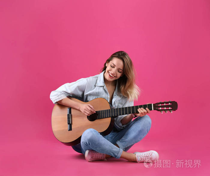 年轻女子弹声吉他的颜色背景