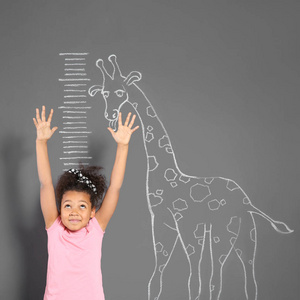 非洲裔美国儿童在粉笔长颈鹿附近测量高度，画灰色的墙