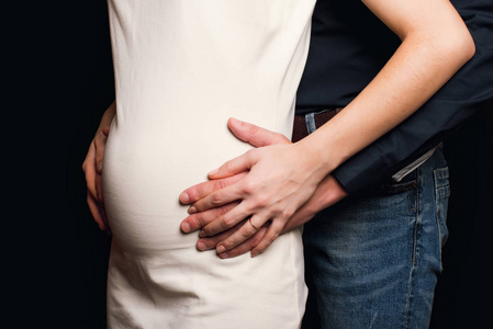 男人抱着怀孕女孩的肚子。一对夫妇正在生孩子