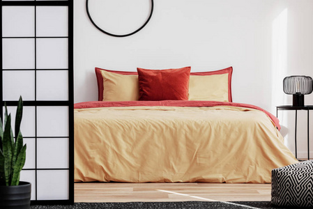 舒适的床，床头柜上有黄色和红色的床上用品工业灯