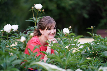 快乐的白种人成年女子微笑着，开着鲜花在花园里放松