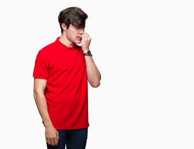 年轻的英俊男子穿着红色T恤，在孤立的背景上看起来压力和紧张，双手咬着嘴的指甲。 焦虑问题。