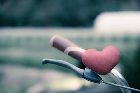 自行车车把上有一个红色的心枕。