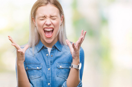 年轻的金发女人在孤立的背景下庆祝疯狂和疯狂的成功，举起手臂和闭上眼睛尖叫兴奋。 赢家概念