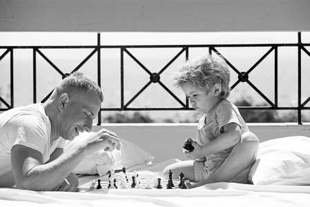 父亲带着儿子在阳台上下棋。孩子和爸爸下棋。幸福家庭的暑假。父亲日与孩子一起家庭旅行。爱和信任作为家庭价值观