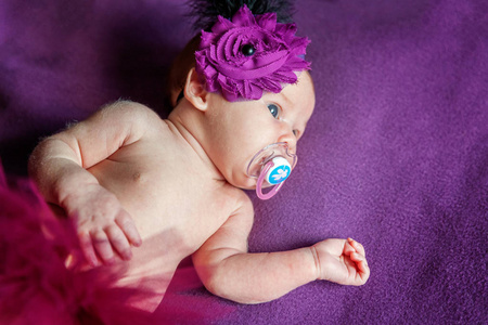 柔和的肖像和平甜蜜的新生婴儿躺在床上，睡在紫色的毯子背景。 甜蜜的梦晚安。 儿童保育概念