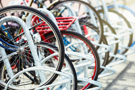 许多不同的自行车停在城市街道的停车场上。 自行车轮锁在金属架上。 荷兰有趣和健康的城市交通。