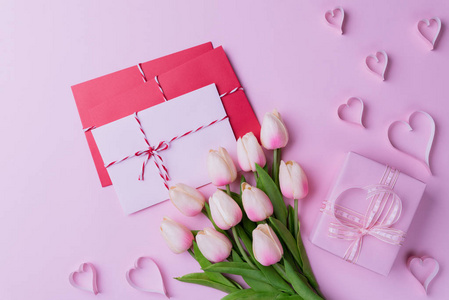 情人节和爱的概念。 粉红色郁金香礼品盒与心和红色粉红色字母封面粉红色背景。
