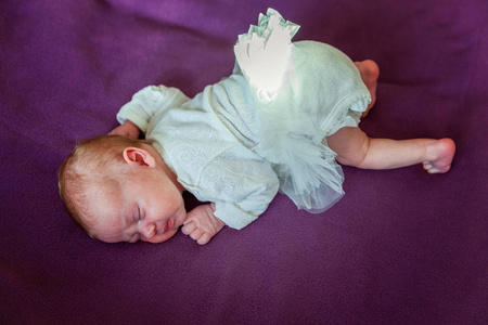柔和的肖像和平甜蜜的新生儿婴儿躺在床上，睡在紫色的毯子背景。做个好梦，晚安。产妇家庭儿童天真关爱概念