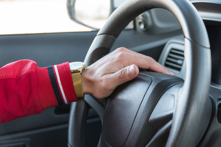 s hand with a watch on the steering wheel of a modern car