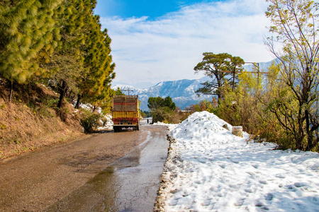 上坡路在巴尼基特达尔豪西希马恰尔邦，印度，侧面充满了雪。 风景优美的冬季景观，从沥青路上覆盖着白雪和树木，在蓝天背景和云彩的道路