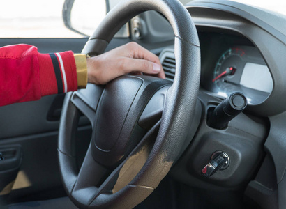 s hand with a watch on the steering wheel of a modern car