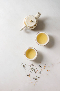 热绿茶在两个传统的中国粘土陶瓷杯和茶壶站在白色大理石背景。 平躺空间