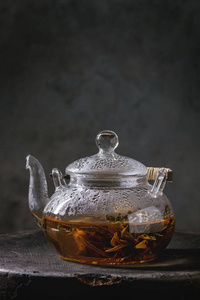 热绿茶在透明玻璃茶壶站在粘土托盘上的黑色大理石桌子。
