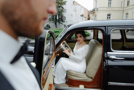美丽快乐的年轻新娘新郎从复古汽车看