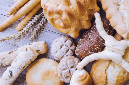 各种新鲜烘焙的硬面包和面包，耳朵在木桌背景上。 乡村复古风格。 上面的风景。
