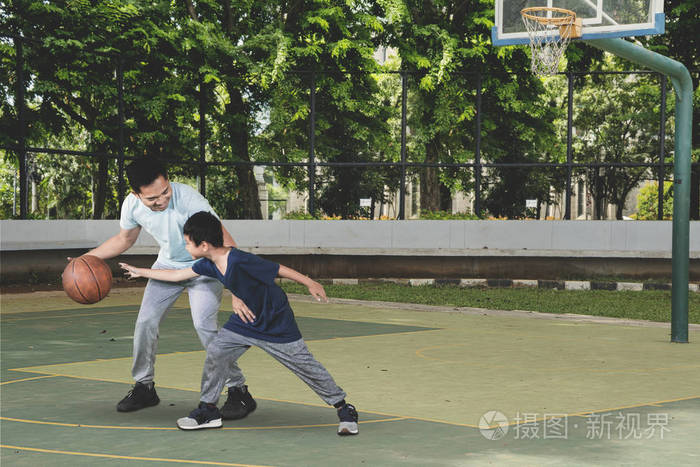 小男孩和他父亲在野外锻炼时打篮球的照片