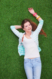 美丽的年轻女子躺在绿色的草地上