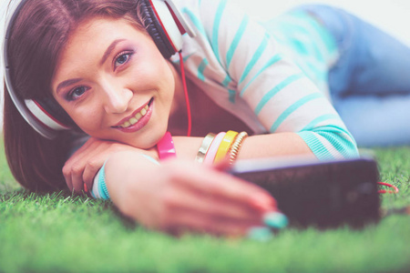美丽的年轻女子躺在绿草自拍的电话。美丽的年轻女子做自拍