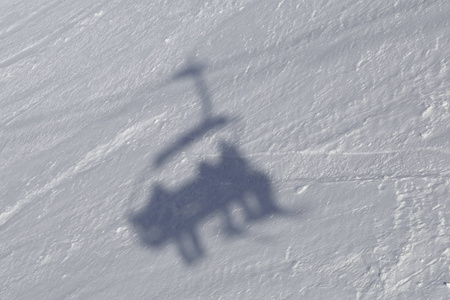 在滑雪场的雪坡上，滑雪者的影子被显示在攀登电梯的地方