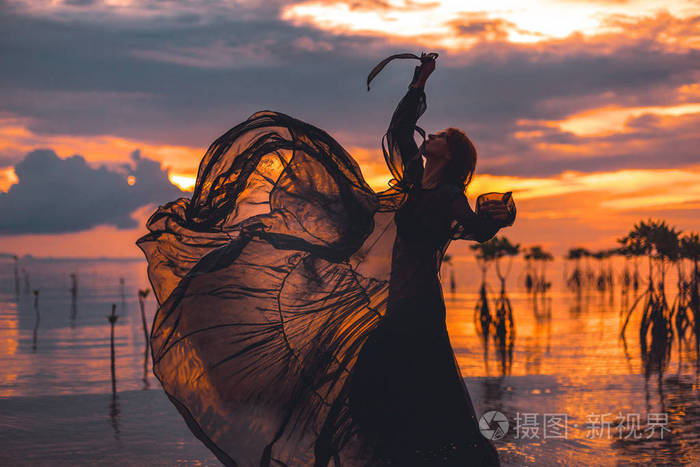 夕阳下,美丽的年轻女子在水中翩翩起舞
