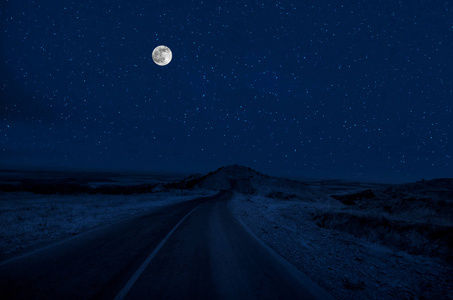 满月之夜，山路穿过森林。 夜晚风景优美的乡村道路，有大月亮