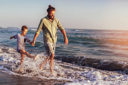  boy child, running and having fun in the sand and waves of a su