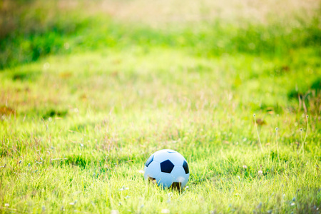 日落光线下的街道足球球。 草地上的足球