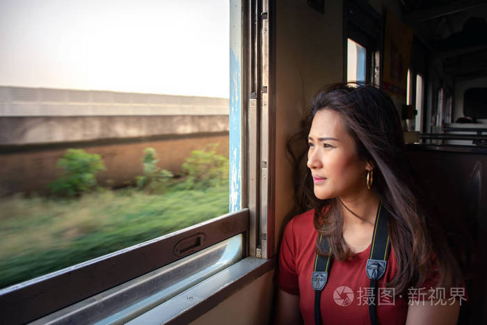 年轻漂亮的亚洲女人坐火车坐在窗户附近,透过火车窗口