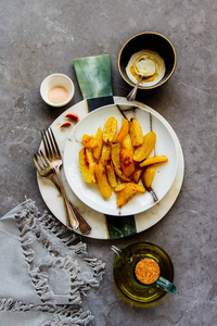 美味的炸土豆楔在盘子里，盐，大蒜和白酱在灰色的混凝土桌子背景上。平躺，俯视图图像